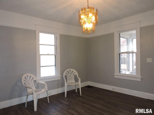 living area with dark wood-type flooring, baseboards, and an inviting chandelier