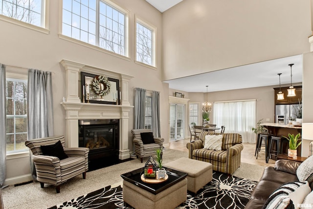 living area with a chandelier, a glass covered fireplace, and baseboards