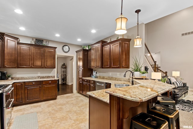 kitchen featuring visible vents, a breakfast bar area, appliances with stainless steel finishes, a peninsula, and a sink