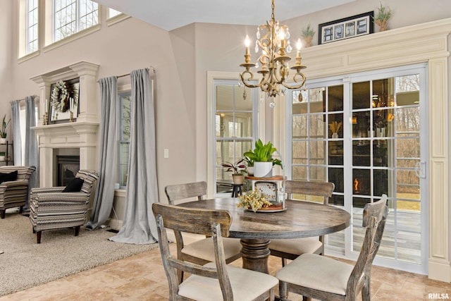 dining room featuring a high ceiling, a fireplace, light colored carpet, and a notable chandelier