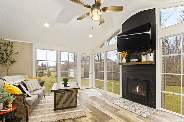 sunroom featuring lofted ceiling, a fireplace with flush hearth, wood ceiling, and ceiling fan