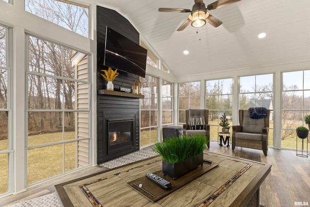 sunroom with lofted ceiling, a fireplace, and a ceiling fan