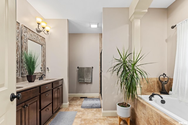 full bath with a shower, double vanity, a sink, tiled tub, and ornate columns