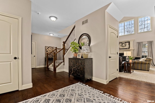 hallway with visible vents, stairway, baseboards, and hardwood / wood-style flooring