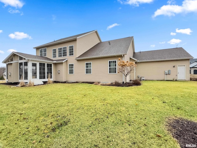 back of property with a sunroom and a lawn