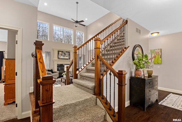 stairs featuring hardwood / wood-style flooring, recessed lighting, visible vents, baseboards, and a glass covered fireplace