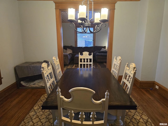 dining space featuring baseboards, wood finished floors, and a notable chandelier