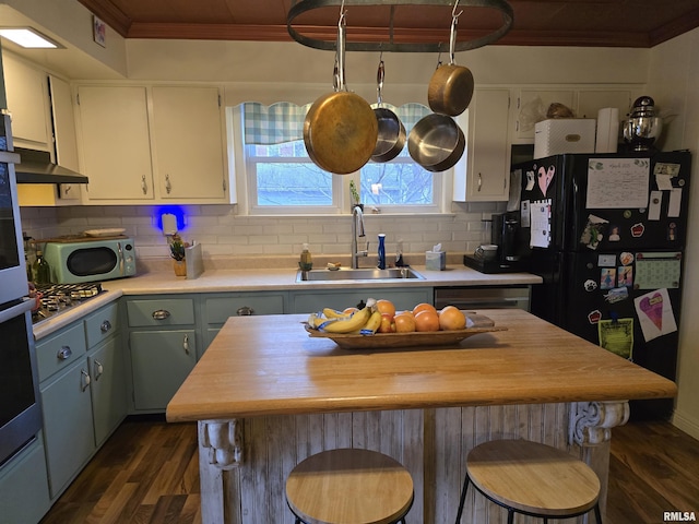 kitchen with dark wood-type flooring, a sink, ornamental molding, freestanding refrigerator, and decorative backsplash