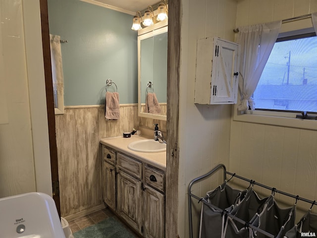 bathroom with a wainscoted wall, wood walls, vanity, and tile patterned floors