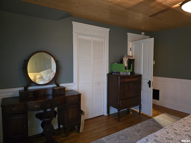 bedroom featuring a closet, wooden ceiling, a wainscoted wall, and wood finished floors