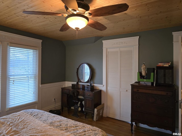 bedroom featuring a ceiling fan, a wainscoted wall, wood ceiling, wood finished floors, and a closet