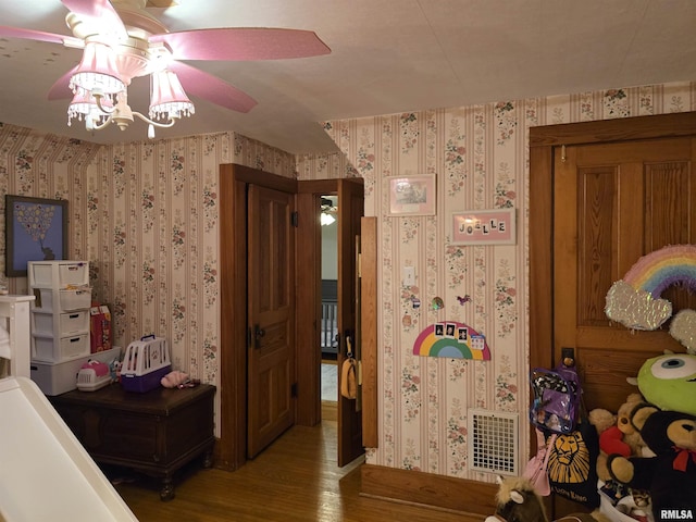 bedroom with wallpapered walls, visible vents, and wood finished floors