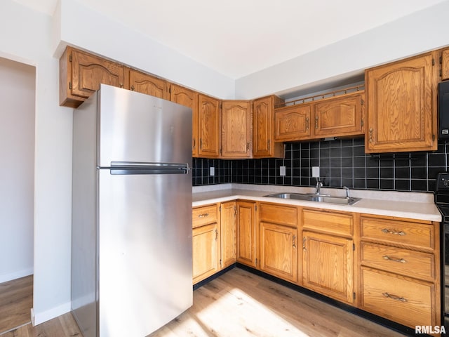 kitchen with a sink, tasteful backsplash, black appliances, and light countertops