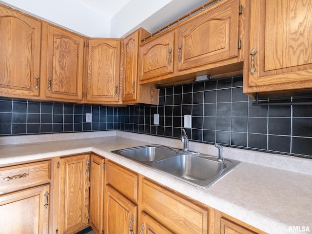 kitchen featuring a sink, decorative backsplash, brown cabinetry, and light countertops