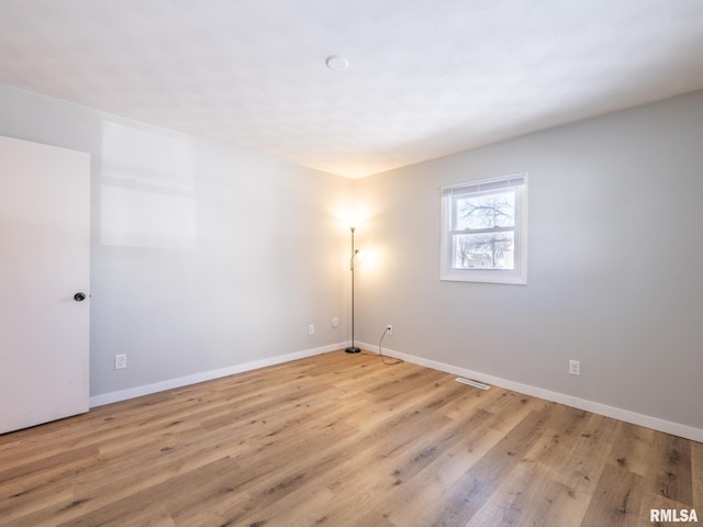 unfurnished room featuring visible vents, wood finished floors, and baseboards