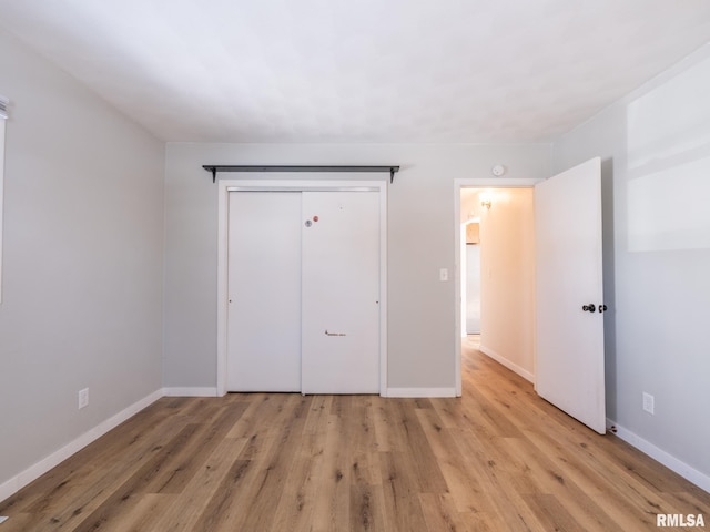 unfurnished bedroom with light wood-style flooring, baseboards, and a closet