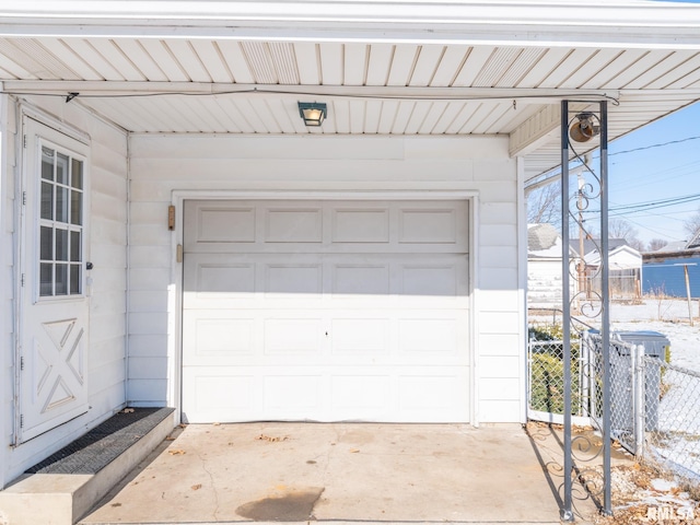 garage with concrete driveway and fence