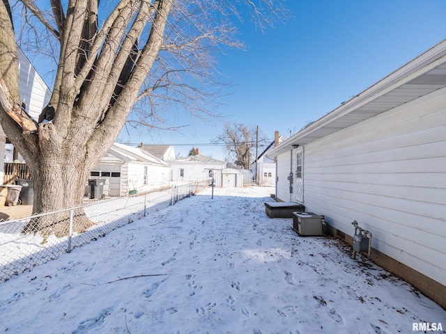 snowy yard with a garage, a residential view, and fence