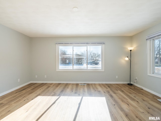 empty room with visible vents, baseboards, and wood finished floors