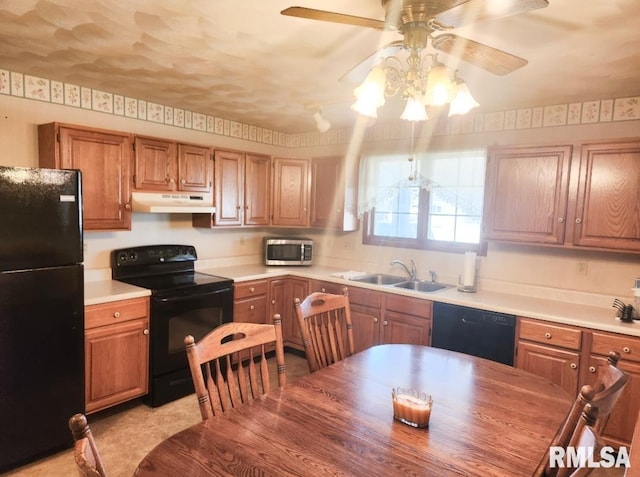 kitchen featuring black appliances, under cabinet range hood, light countertops, and a sink