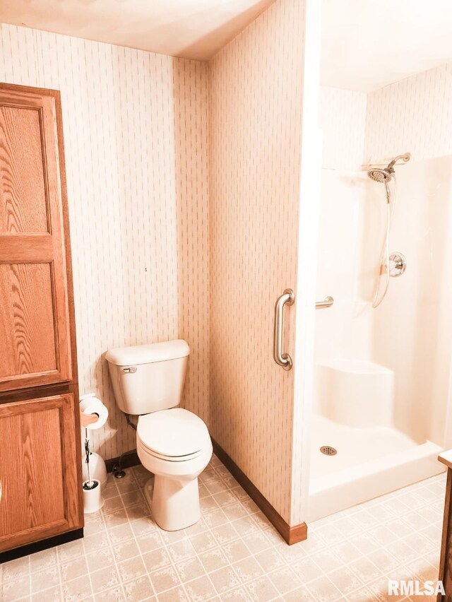 bathroom featuring toilet, wallpapered walls, a shower stall, and tile patterned floors