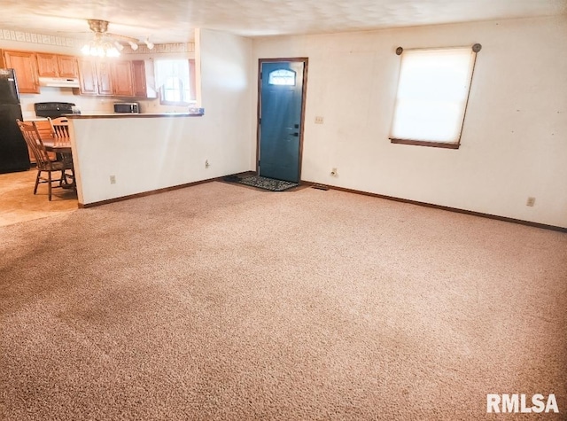 unfurnished living room featuring baseboards and light colored carpet