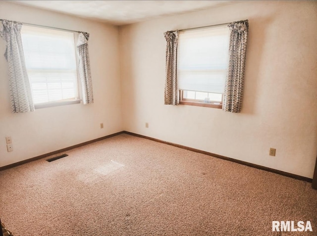 carpeted spare room featuring visible vents and baseboards