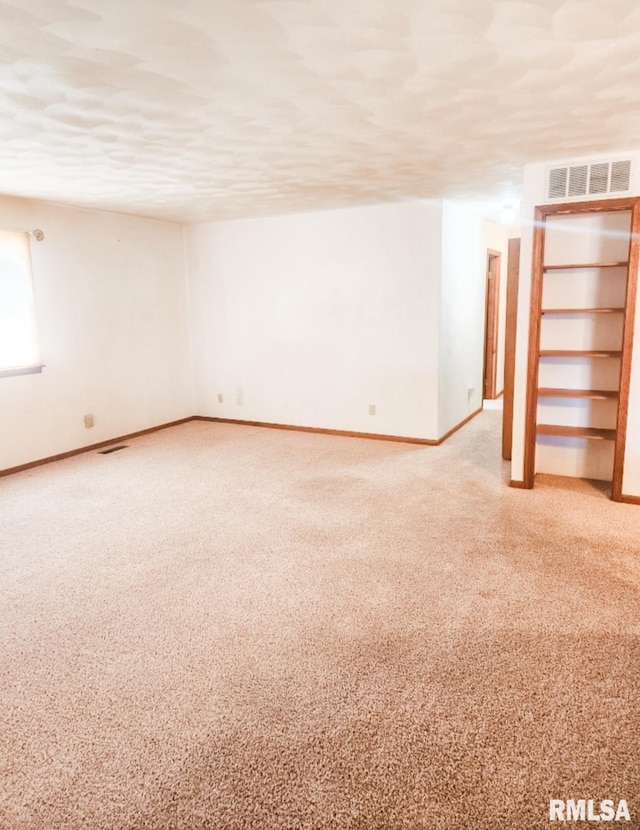 unfurnished room featuring carpet floors, baseboards, visible vents, and a textured ceiling