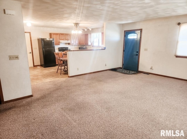 unfurnished living room featuring baseboards, a textured ceiling, and light colored carpet