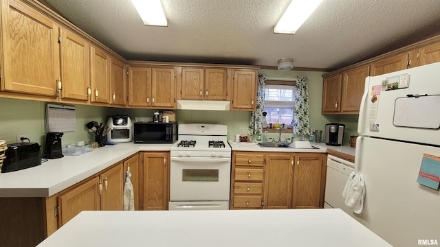 kitchen featuring light countertops, a sink, a textured ceiling, under cabinet range hood, and white appliances