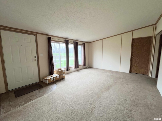 unfurnished living room featuring a textured ceiling, ornamental molding, and light colored carpet