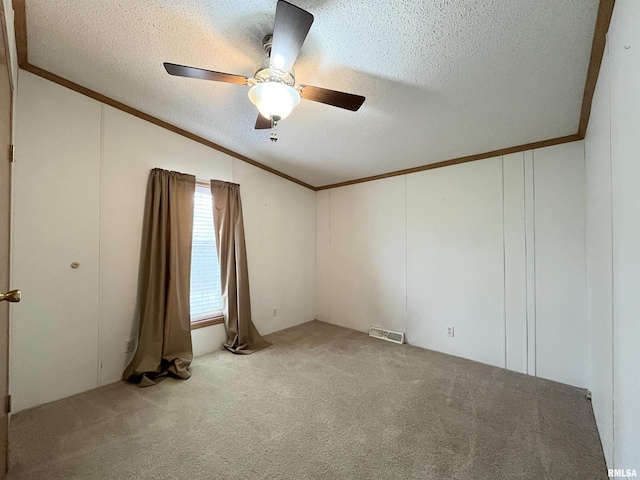 carpeted spare room with a textured ceiling, visible vents, vaulted ceiling, and crown molding