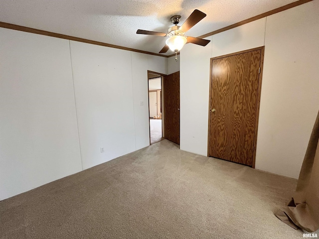 unfurnished bedroom featuring crown molding, a textured ceiling, carpet floors, ceiling fan, and a closet