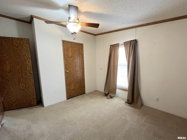 unfurnished bedroom featuring a ceiling fan, crown molding, carpet, and a textured ceiling