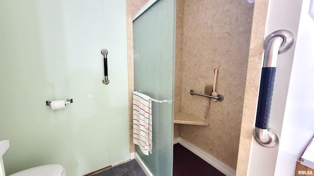 bathroom with toilet and a shower with door