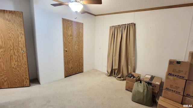 unfurnished bedroom featuring ceiling fan, crown molding, carpet floors, and a textured ceiling