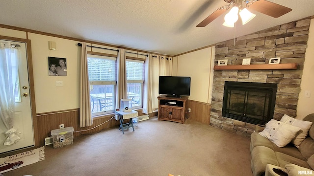 carpeted living room with a textured ceiling, vaulted ceiling, ceiling fan, and wainscoting