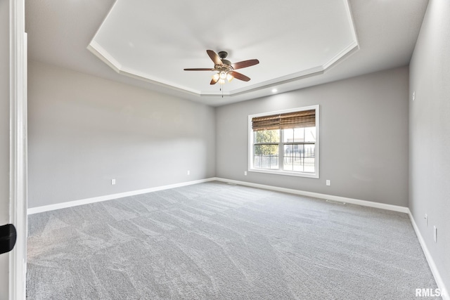 empty room with visible vents, ceiling fan, baseboards, carpet floors, and a raised ceiling