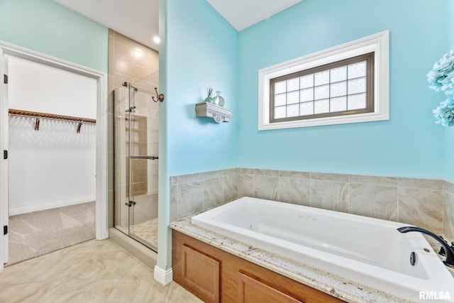 bathroom featuring a walk in closet, a shower stall, and a garden tub