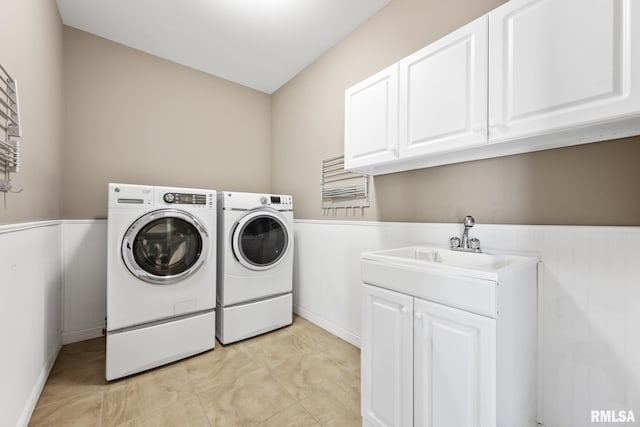 laundry area with washer and clothes dryer, cabinet space, wainscoting, and a sink