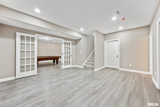 below grade area featuring light wood finished floors, baseboards, stairs, recessed lighting, and french doors