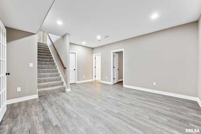 below grade area featuring recessed lighting, light wood-style flooring, stairs, and baseboards