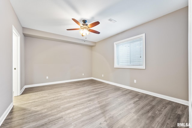 spare room with ceiling fan, wood finished floors, visible vents, and baseboards