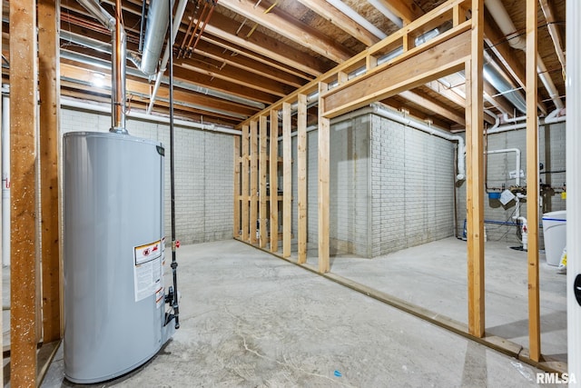 unfinished basement featuring gas water heater and brick wall