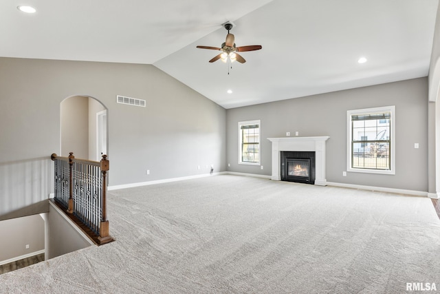 living area with baseboards, carpet, a fireplace with flush hearth, and vaulted ceiling