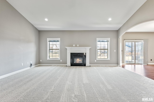 unfurnished living room with a high end fireplace, carpet flooring, recessed lighting, and baseboards