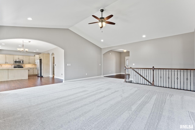 unfurnished living room with lofted ceiling, recessed lighting, arched walkways, ceiling fan with notable chandelier, and dark carpet