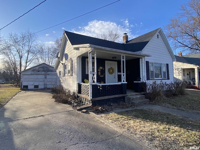 bungalow-style home with a porch, a garage, an outdoor structure, roof with shingles, and a chimney