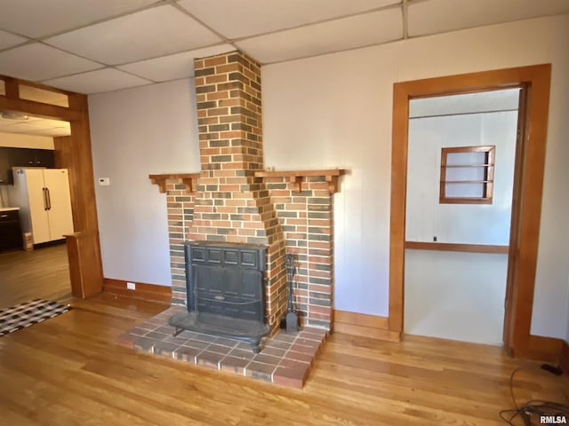 unfurnished living room with baseboards, a drop ceiling, and wood finished floors