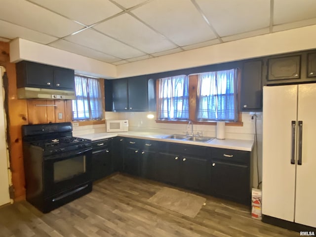 kitchen with white appliances, a sink, dark wood finished floors, and under cabinet range hood